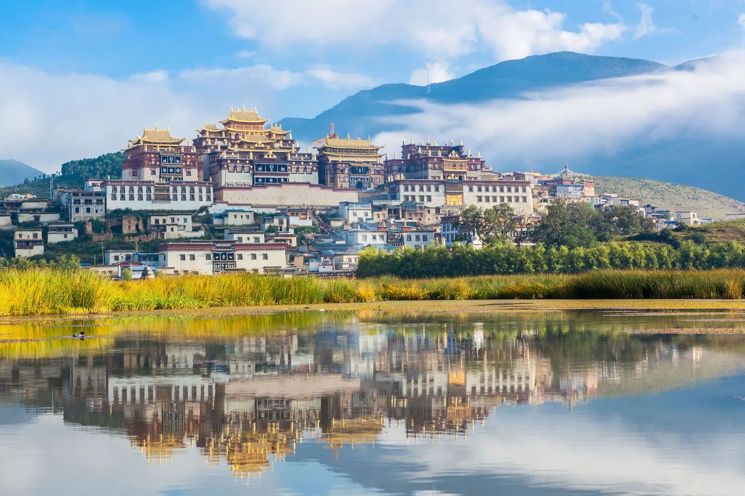 The magnificent Songzanlin Monastery reflected on the lake in Shangri-La, showcasing Tibetan Buddhist architecture and the beauty of Yunnan.