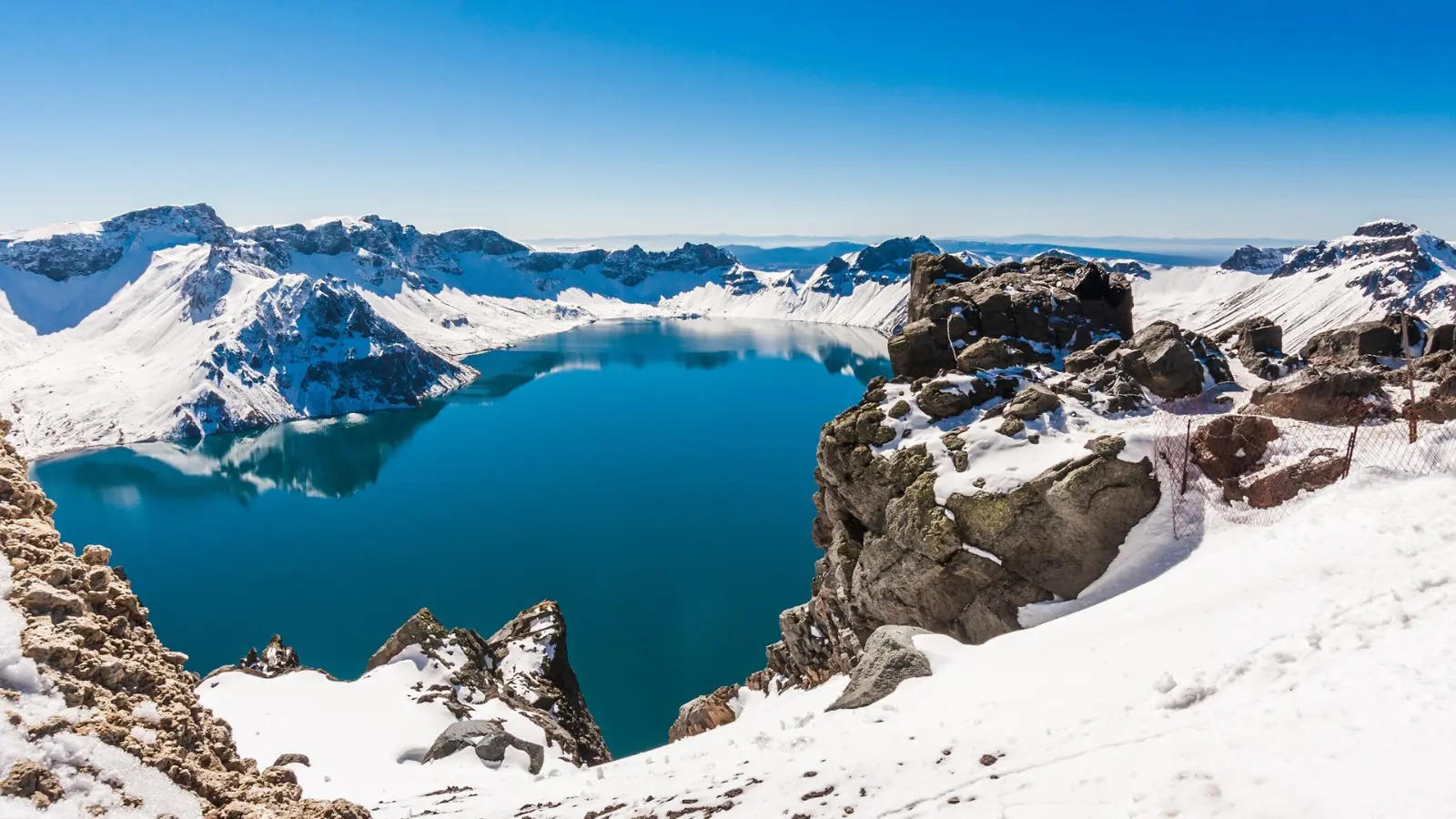 Snow-covered Changbai Mountain with a crystal-clear volcanic lake surrounded by rugged peaks