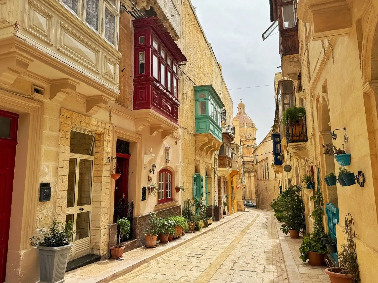 A charming street in Valletta, Malta, lined with colorful traditional Maltese balconies, historic limestone buildings, and picturesque alleys showcasing the city's UNESCO World Heritage architecture.