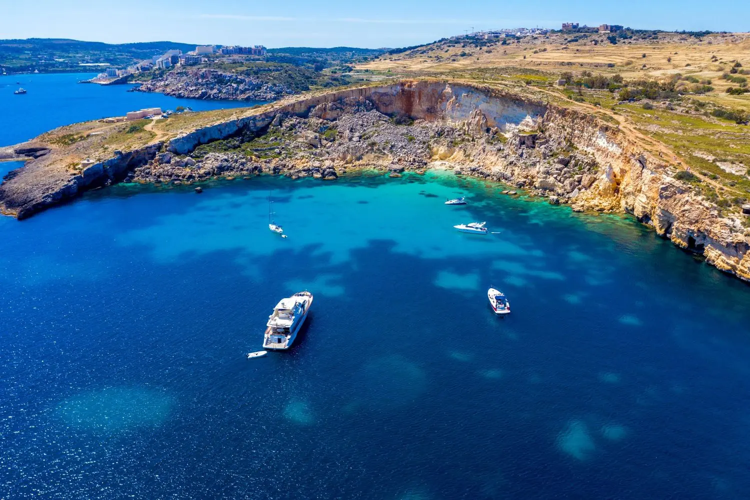 The stunning St. Peter's Pool in Malta, featuring crystal-clear turquoise waters, dramatic limestone cliffs, and a secluded natural swimming cove along the Mediterranean coast.