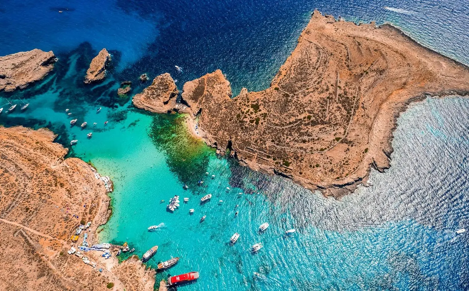 The breathtaking Blue Lagoon on Comino Island, Malta, featuring crystal-clear turquoise waters, white sandy seabeds, scenic boat tours, swimming, snorkeling, and spectacular Mediterranean coastal views.