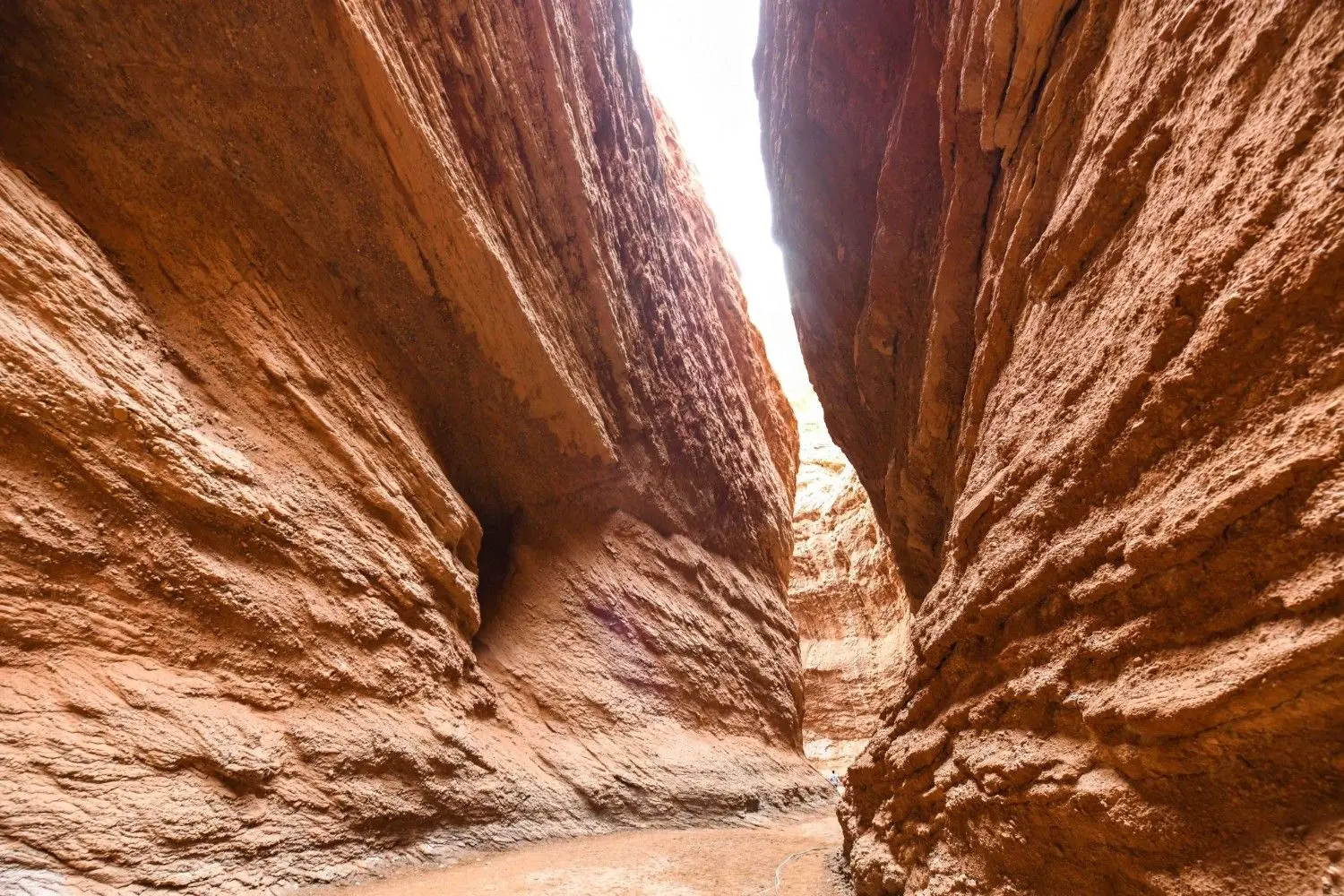 The spectacular Tianshan Grand Canyon in Xinjiang, China, featuring towering red sandstone cliffs, dramatic rock formations, and a breathtaking natural canyon carved through the Tianshan Mountains.