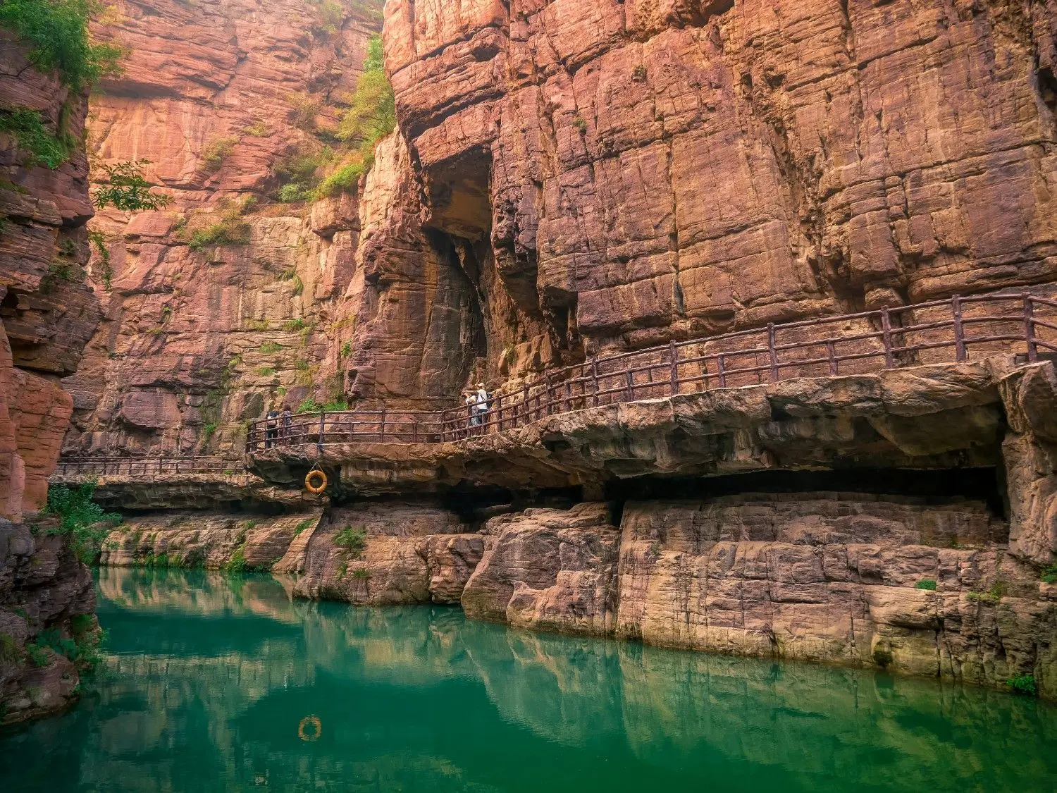 Emerald waters flowing through the towering red sandstone cliffs of Hongshi Gorge (Red Stone Gorge) at Yuntai Mountain Geopark in Henan, China, showcasing one of China's most spectacular canyon landscapes.