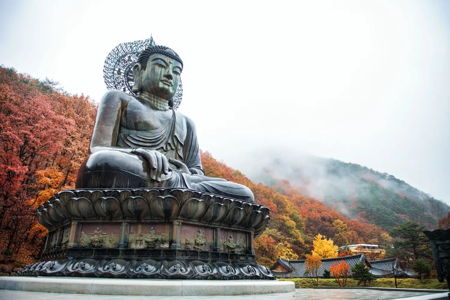 Great Buddha of Sinheungsa Temple in Seoraksan National Park, South Korea, surrounded by vibrant autumn foliage and misty mountain scenery, showcasing one of Korea's most iconic Buddhist landmarks.
