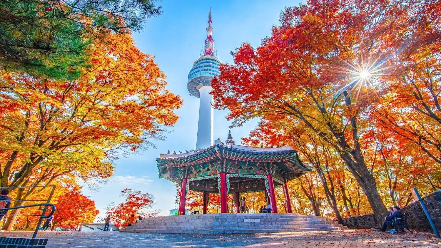 N Seoul Tower in Namsan Park, South Korea, surrounded by vibrant autumn maple trees and a traditional Korean pavilion, offering one of Seoul's most iconic panoramic viewpoints.