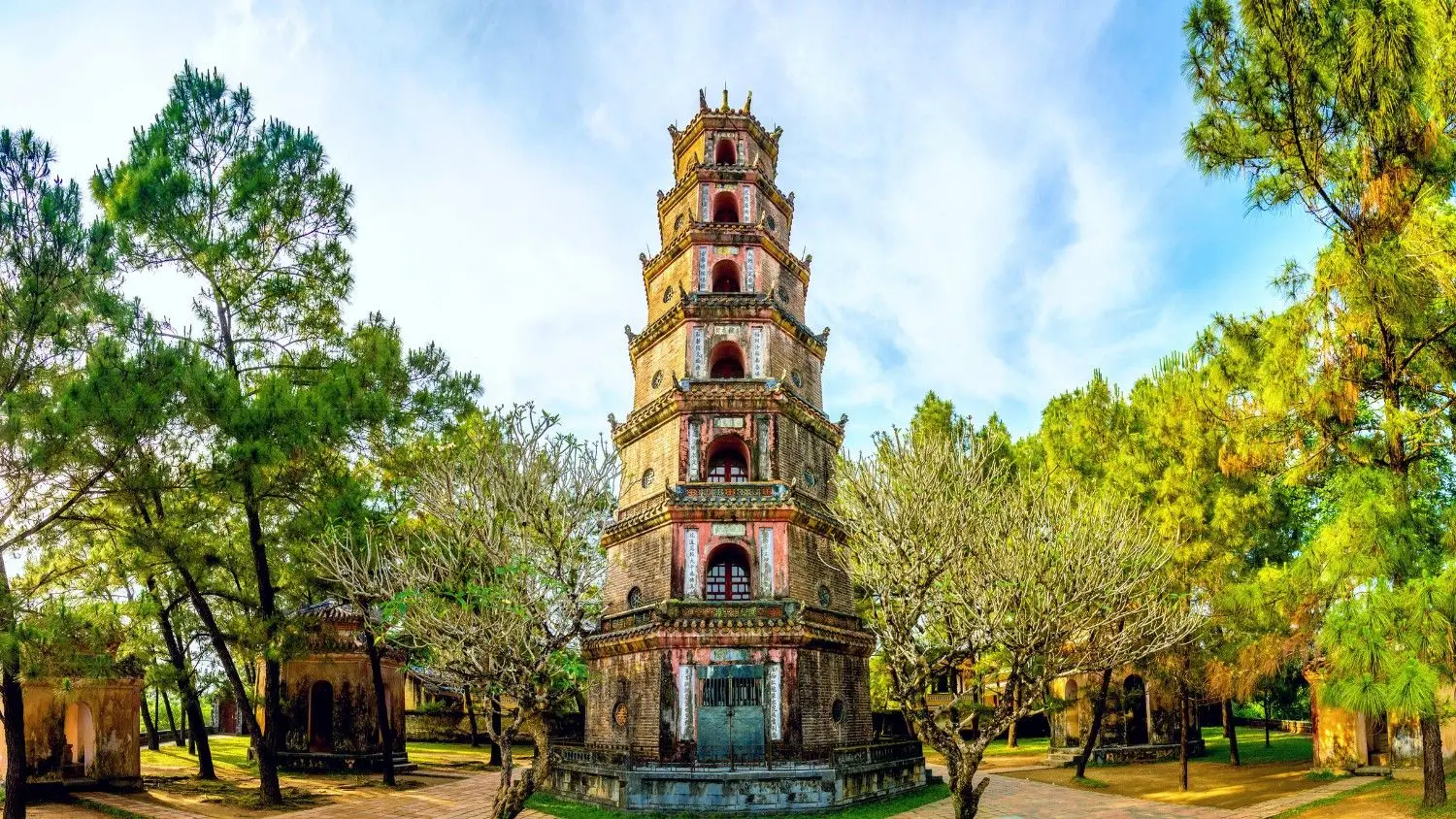 Thien Mu Pagoda (Thiên Mụ Pagoda) in Hue, Vietnam, featuring the iconic seven-story Phuoc Duyen Tower surrounded by lush pine trees, one of Vietnam's most famous Buddhist landmarks.