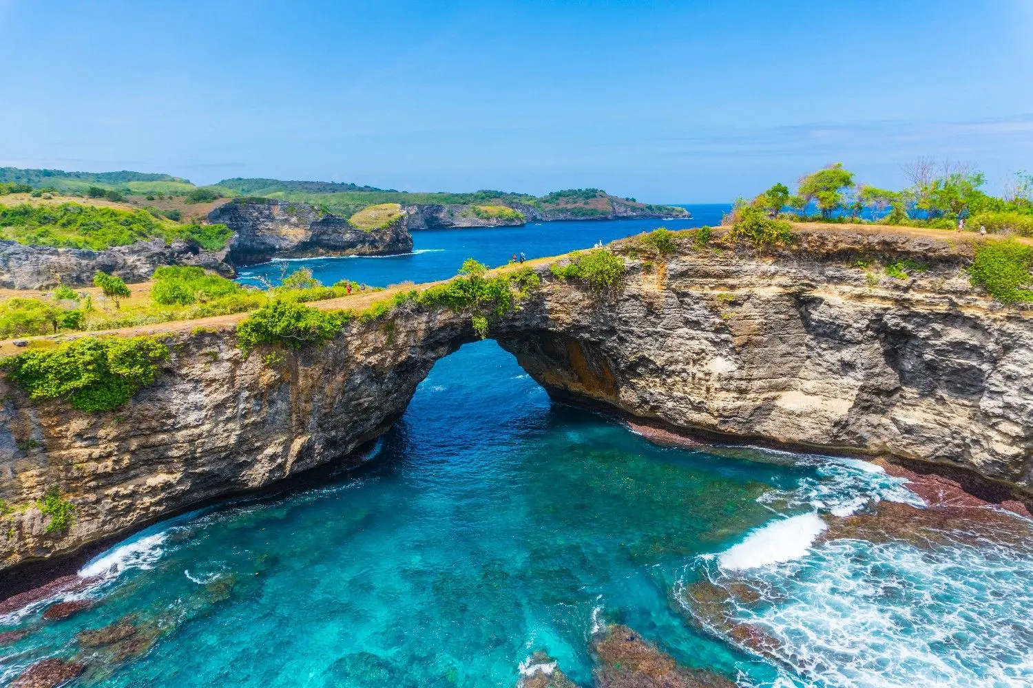 Broken Beach (Pasih Uug) on Nusa Penida, Bali, Indonesia, featuring a spectacular natural limestone arch, crystal-clear turquoise waters, and dramatic coastal cliffs. One of Bali's most iconic natural attractions, renowned for its breathtaking ocean scenery and unique geological formations.