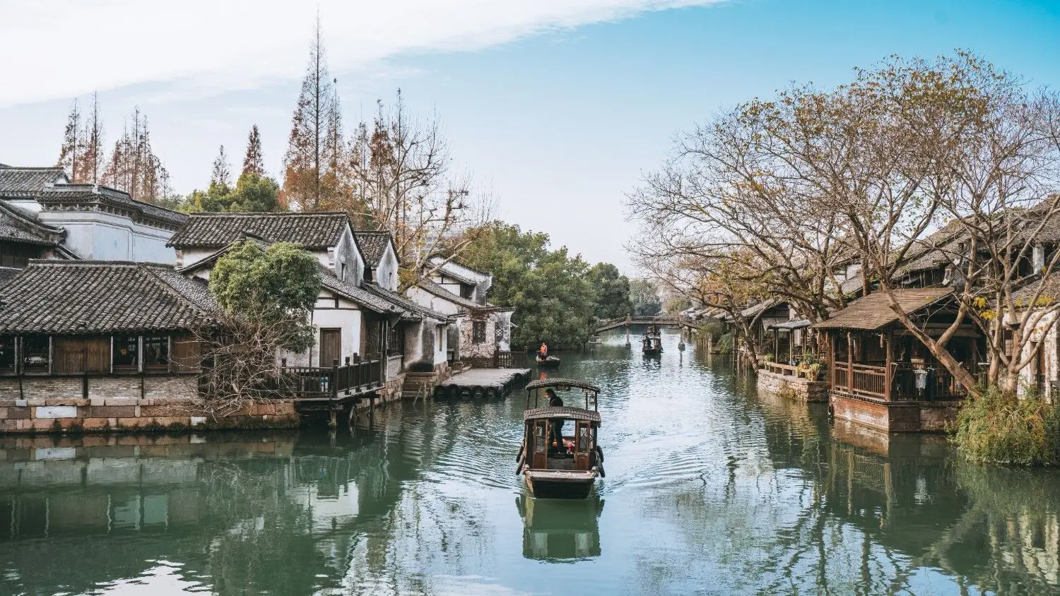West Lake Cruise in Hangzhou, Zhejiang, China, featuring a traditional wooden boat gliding across tranquil waters surrounded by historic architecture, willow trees, and picturesque lakeside scenery. One of China's most iconic UNESCO World Heritage destinations, renowned for its timeless beauty and cultural heritage.