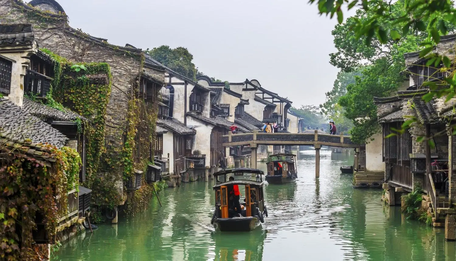 Wuzhen Water Town in Tongxiang, Zhejiang, China, featuring tranquil canals, traditional Jiangnan architecture, historic stone bridges, and wooden boats gliding through centuries-old waterways. One of China's most famous ancient water towns, renowned for its cultural heritage and picturesque scenery.