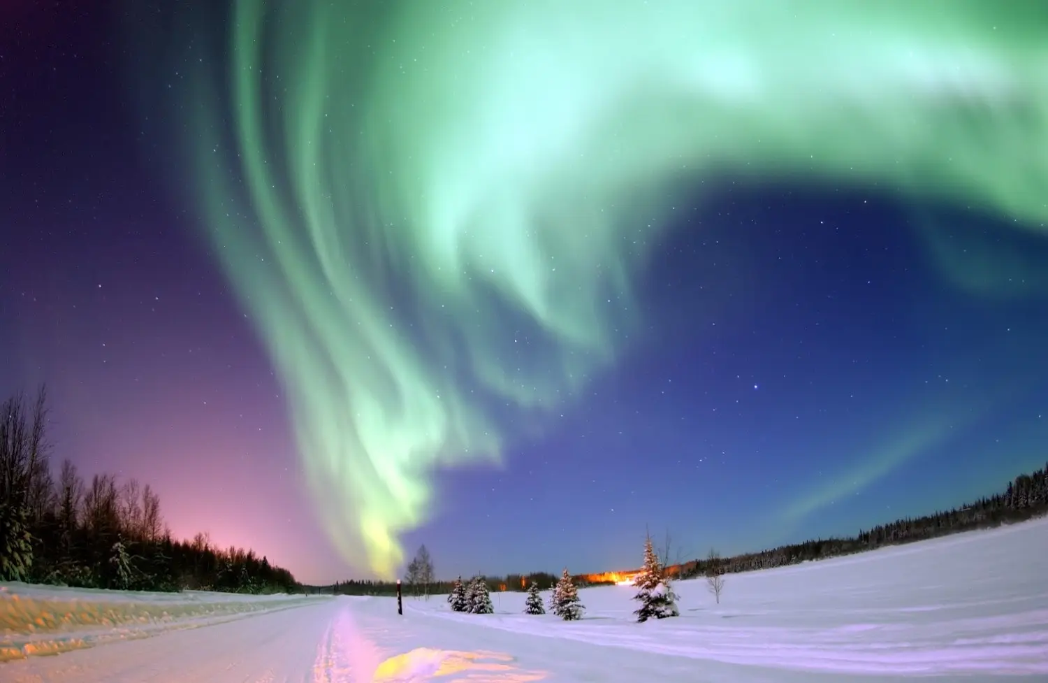 Northern Lights (Aurora Borealis) over the snowy Arctic landscape of Murmansk, Russia, featuring spectacular green aurora dancing across the night sky. One of the world's most breathtaking natural phenomena and a highlight of winter travel in the Russian Arctic.