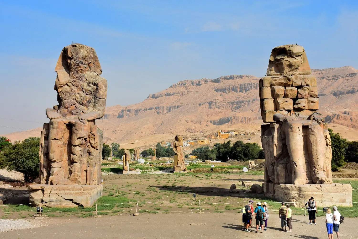Colossi of Memnon in Luxor, Egypt, featuring two monumental stone statues of Pharaoh Amenhotep III against the dramatic Theban Mountains. One of Luxor’s iconic ancient Egyptian landmarks.